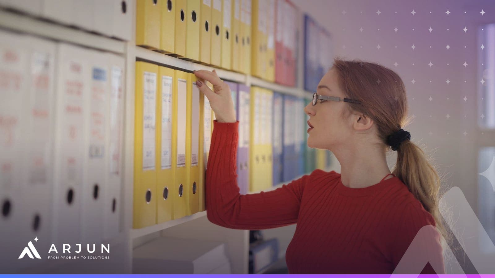 An office employee reaching for a labelled ring binder on a shelf of company files