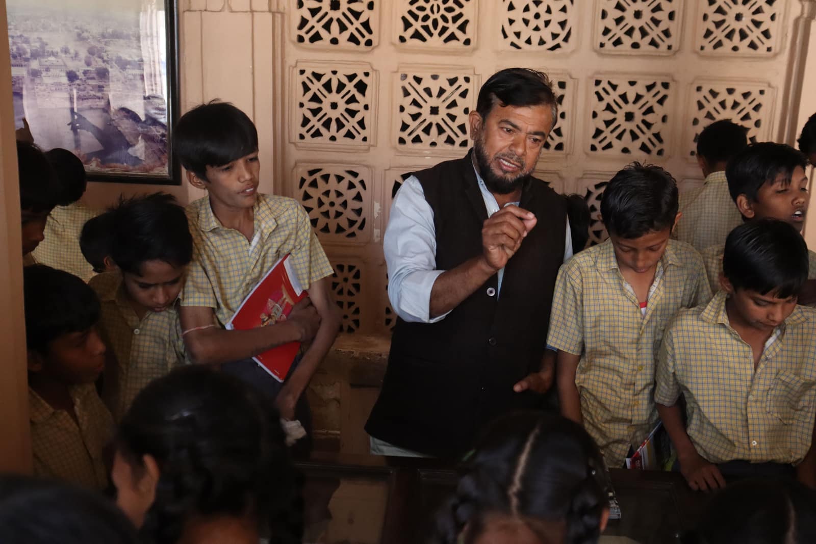 A teacher leaning in to guide a group of school students during a lesson